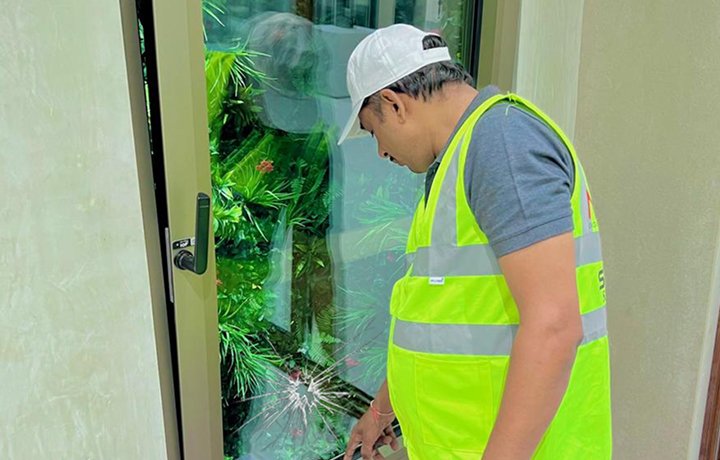 Technician inspecting cracked window glass panel for replacement
