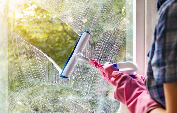 Professional window cleaning with squeegee on glass